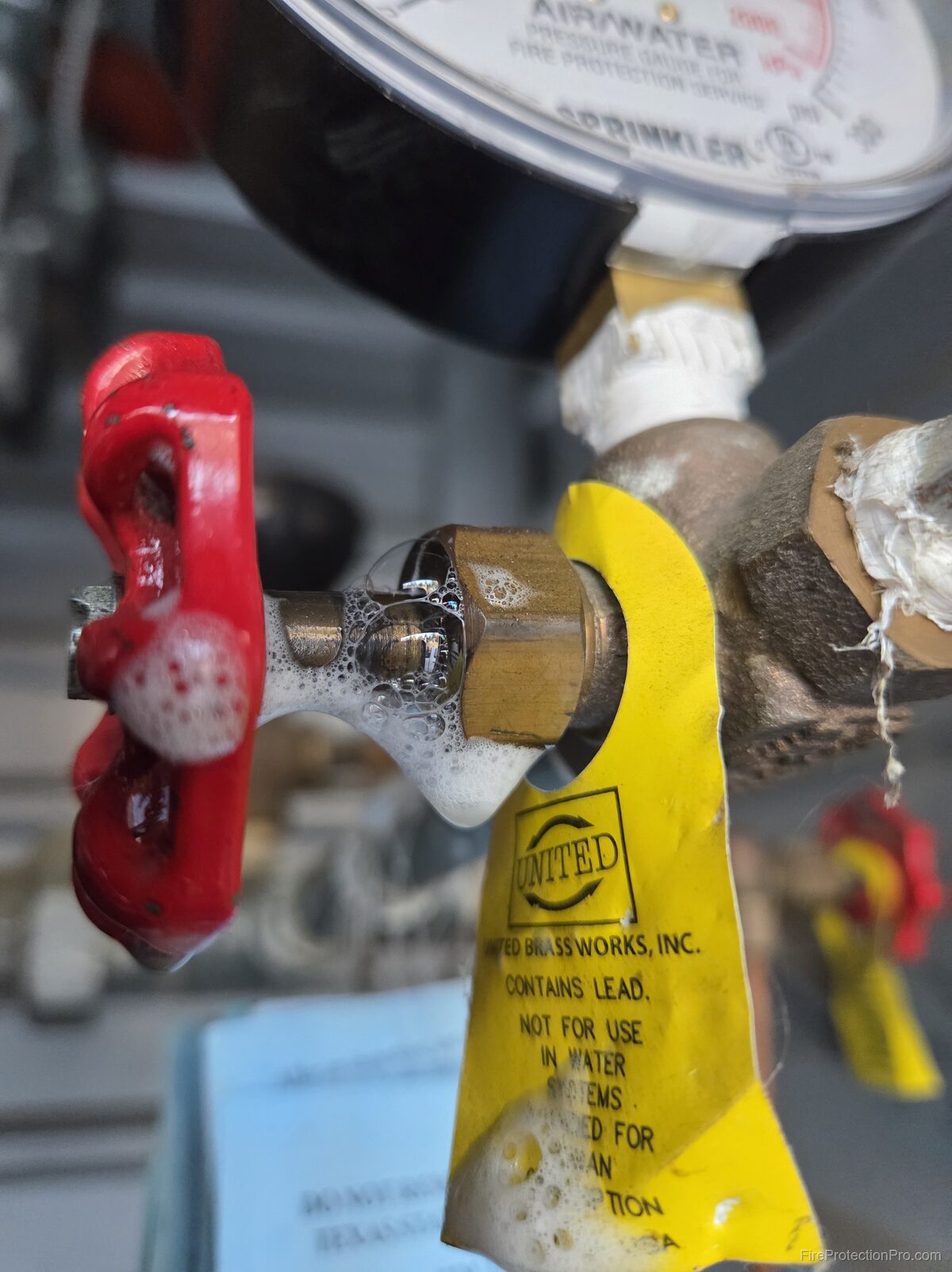 Sprinkler riser gauge valve with soap bubble leak test showing bubbles at the fitting